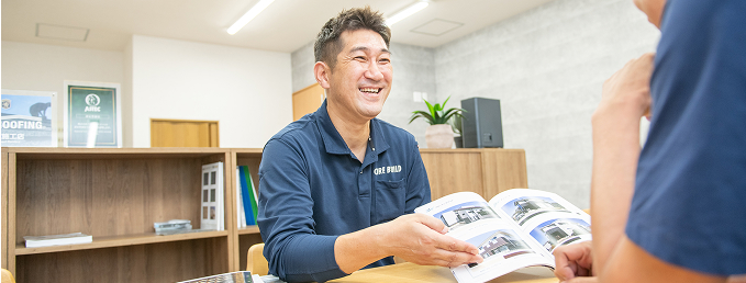 資料を手に持ち、笑顔で顧客に説明している