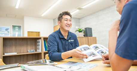 カタログを見せながら笑顔で案内する接客中のスタッフ