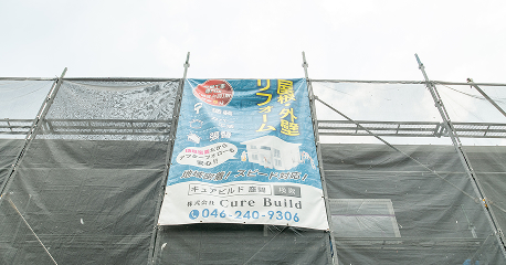 建物の足場に掲げられた「屋根・外壁リフォーム」の垂れ幕