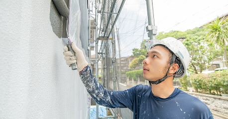 外壁にローラーで塗装を行う作業員