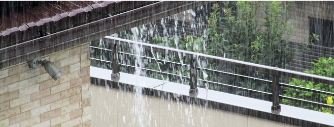 大雨により屋根から雨水が溢れ出し、勢いよく流れ落ちている