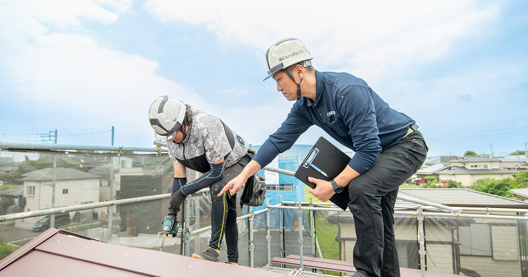 屋根の上で作業中の職人に指示を出している監督者の様子