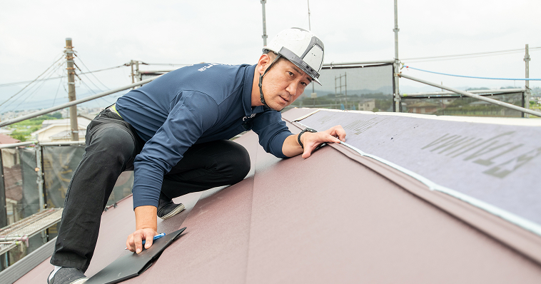 屋根に登り、点検作業を行っている